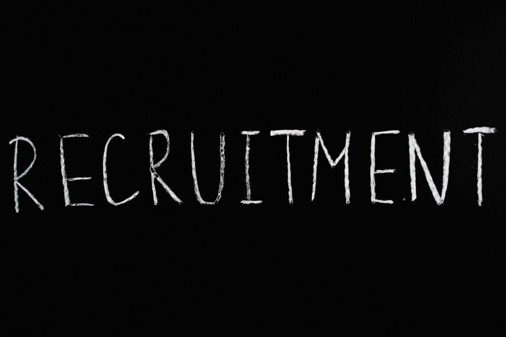 Chalk-written 'RECRUITMENT' on a black chalkboard, ideal for HR and hiring themes.